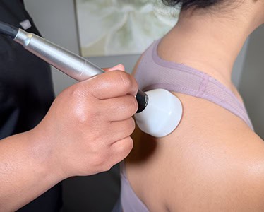 Class IV laser therapy handpiece applied to a patient's shoulder during treatment in Encinitas