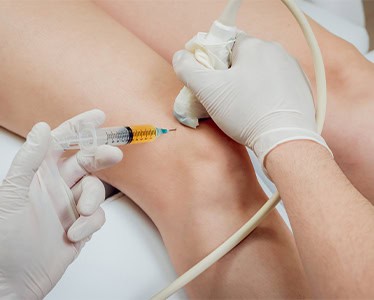 Provider administering a PRP regenerative medicine injection guided by ultrasound near a patient's knee in Encinitas, CA